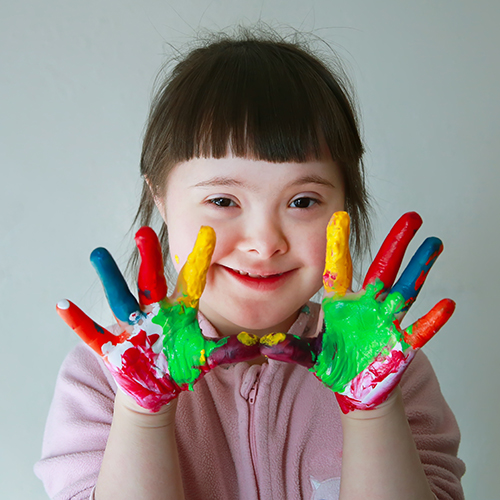 Cute little autistic girl with painted hands. Isolated on grey background.