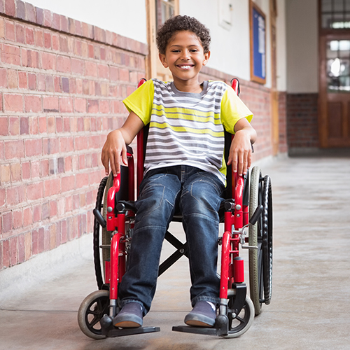 Cute disabled pupil smiling at camera in hall at the elementary school