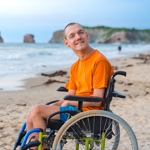 Portrait of a disabled person in a wheelchair on the beach enjoying the freedom of the sea and nature